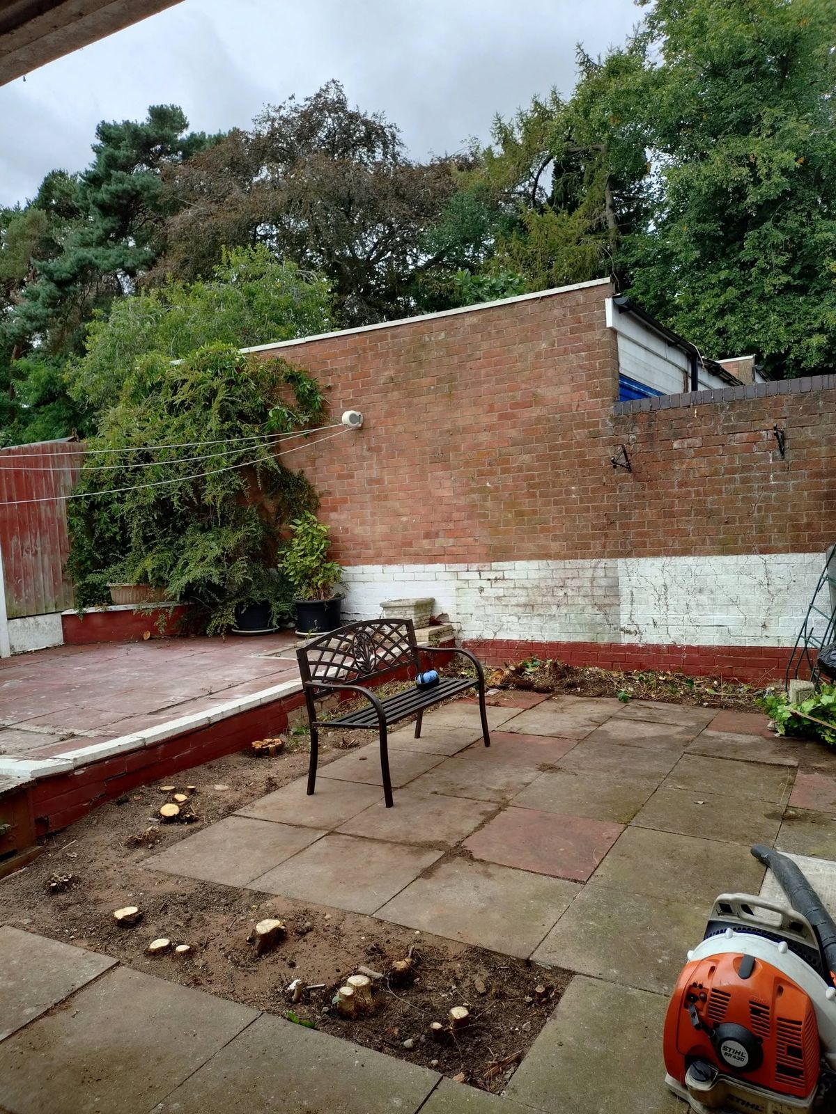 A cleared paved courtyard with a bench after the work